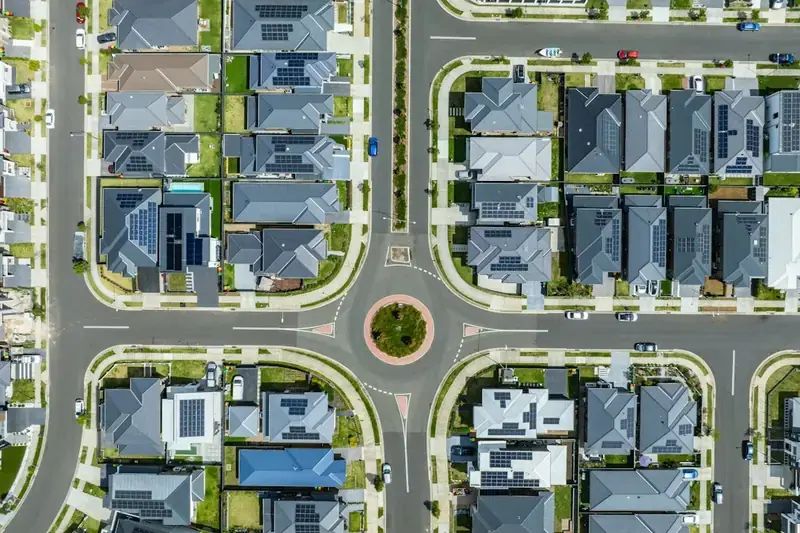Aerial view of a suburban street grid with a roundabout and rooftop solar panels